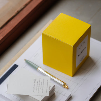 Yellow box, pen, and notepad on a wooden surface