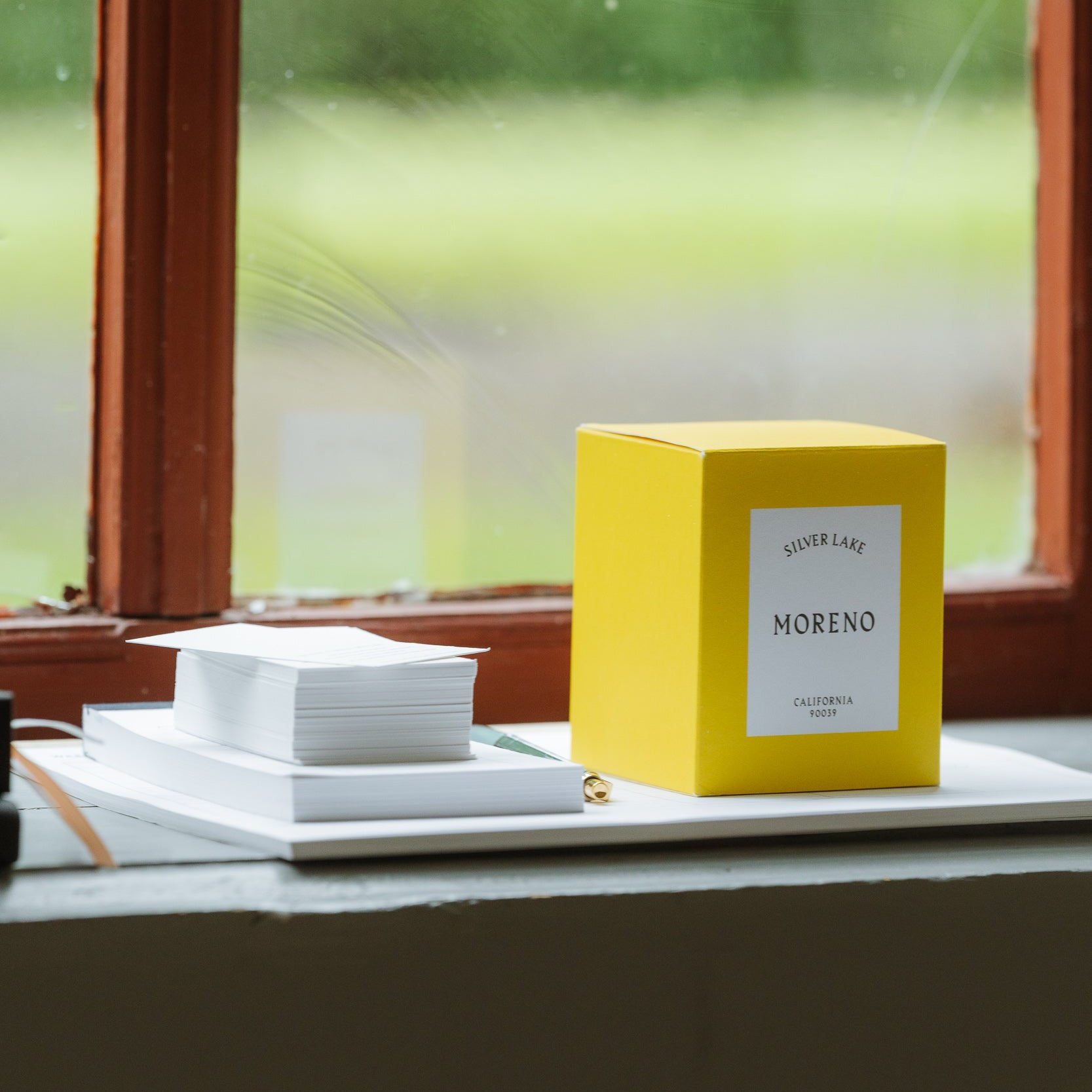 Yellow box labeled 'MORENO' on a surface with a window in the background